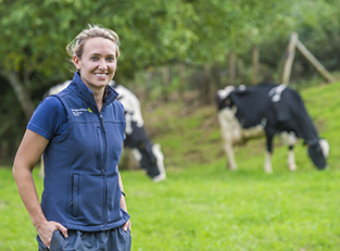 Andrea turner standing in field with cow in background